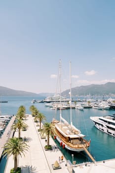 Large sailing yacht with a bridge lowered to the shore stands at the marina pier. High quality photo