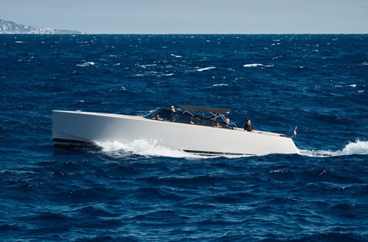 Monaco, Monte Carlo, 28 September 2022 - A motorboat with people is sailing at high speed in the sea near Monaco, island on background. High quality photo