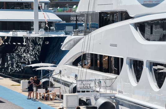 Monaco, Monte Carlo, 28 September 2022 - Invited wealthy clients inspect megayachts at the largest fair exhibition in the world yacht show MYS, port Hercules, yacht brokers, sunny weather. High quality photo