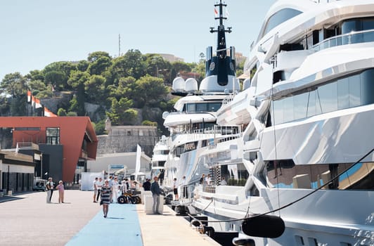 Monaco, Monte Carlo, 28 September 2022 - Invited wealthy clients inspect megayachts at the largest fair exhibition in the world yacht show MYS, port Hercules, yacht brokers, sunny weather. High quality photo