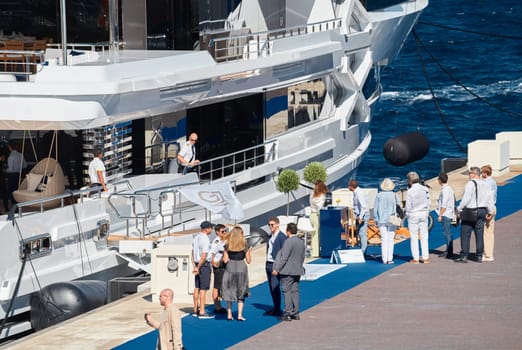 Monaco, Monte Carlo, 28 September 2022 - Invited wealthy clients inspect megayachts at the largest fair exhibition in the world yacht show MYS, port Hercules, yacht brokers, sunny weather. High quality photo