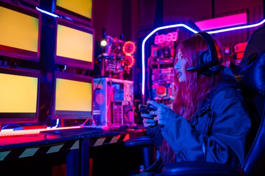 Gamer using joystick controller for virtual tournament plays online video game with computer neon lights, woman wear gaming headphones playing live stream esports games console gaming room