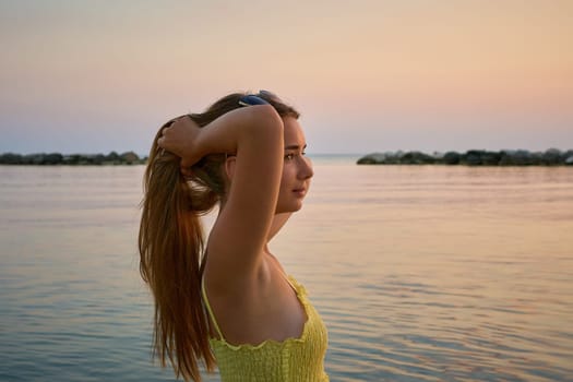 Young female traveler posing on the beach by the sea at sunrise and sharing her adventure travel.