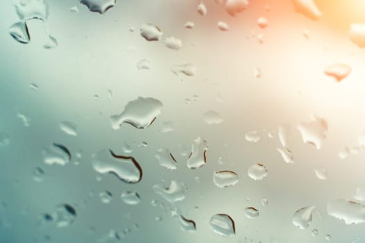 Raindrops on glass against blue sky. Window view background screensaver. Place for text banner.