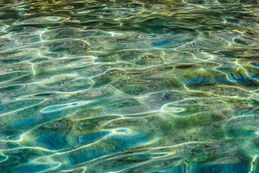 Emerald sea water in sunshine glow as surface background. Summer holidays concept