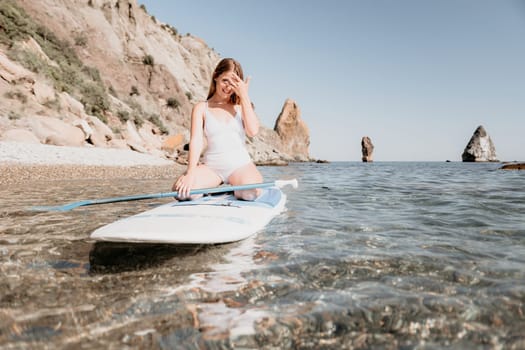 Close up shot of happy young caucasian woman looking at camera and smiling. Cute woman portrait in bikini posing on a volcanic rock high above the sea