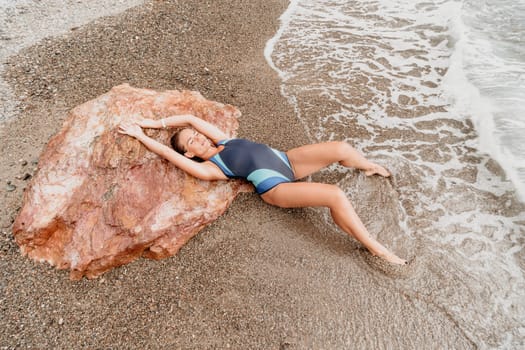 Woman travel sea. Young Happy woman in a long red dress posing on a beach near the sea on background of volcanic rocks, like in Iceland, sharing travel adventure journey