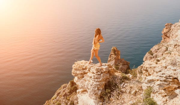 Woman travel sea. Happy tourist taking picture outdoors for memories. Woman traveler looks at the edge of the cliff on the sea bay of mountains, sharing travel adventure journey.