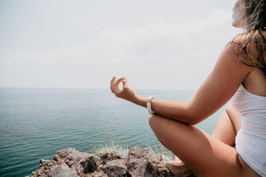 Woman meditating in yoga pose silhouette at the ocean, beach and rock mountains. Motivation and inspirational fit and exercising. Healthy lifestyle outdoors in nature, fitness concept.