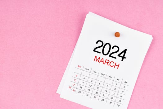 March 2024 calendar page and wooden push pin on pink Color background.