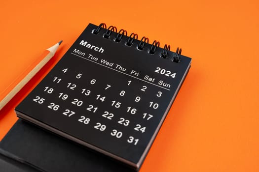 March 2024 desk calendar with pencil on orange color background.