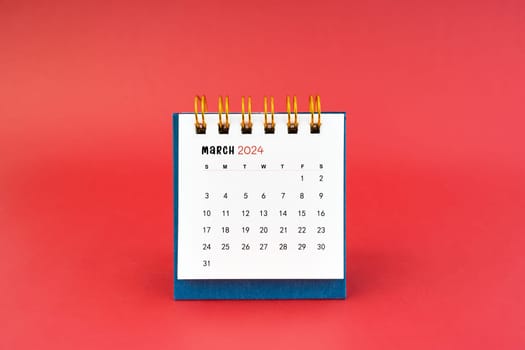 March 2024 white desk calendar on red color background.