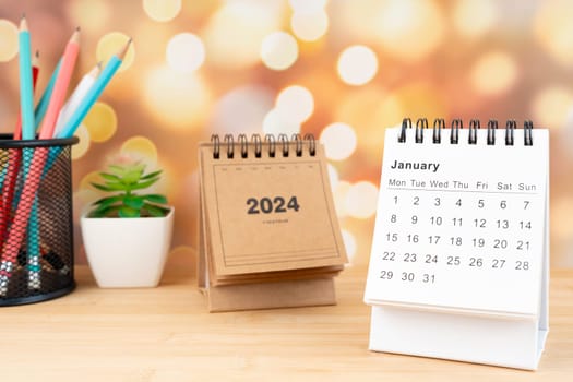 White January 2024 desk calendar on wooden table with gold light bokeh background. New Year Concept.