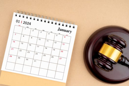 Desk calendar for January 2024 and judge's gavel on brown background.