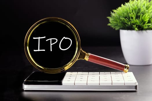 IPO abbreviation of Initial Public Offering text seen with a magnifying glass on a black background
