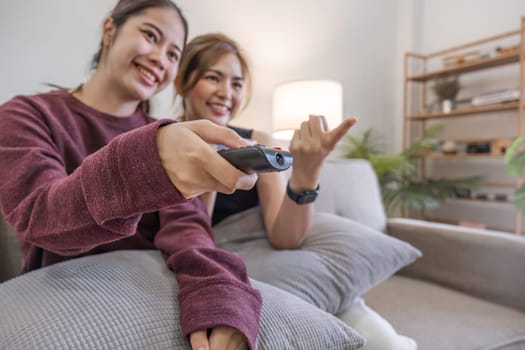 Two Asian sisters watch TV together. relax at home Enjoy watching television.