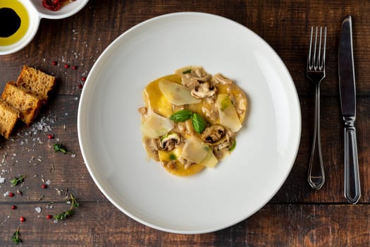 Italian dish ravioli with mushrooms and parmesan on wooden table