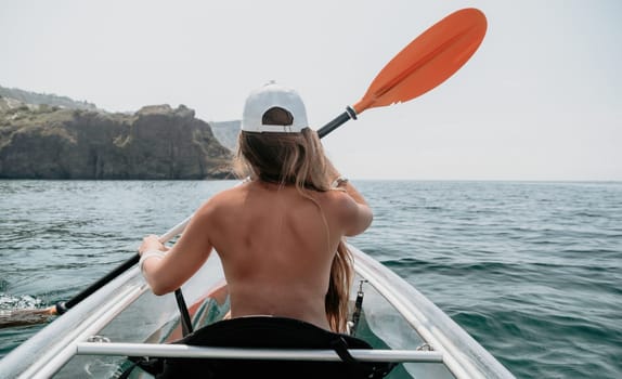 Woman in kayak back view. Happy young woman with long hair floating in transparent kayak on the crystal clear sea. Summer holiday vacation and cheerful female people having fun on the boat.