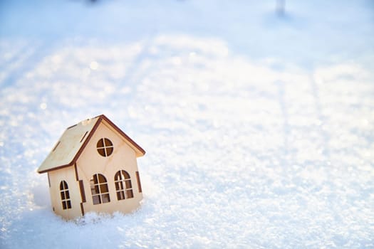 Wooden toy house on snow, natural abstract background. winter season concept. symbol of cozy, loving family home. construction, sales, rental concept. Christmas and new year holidays. copy space