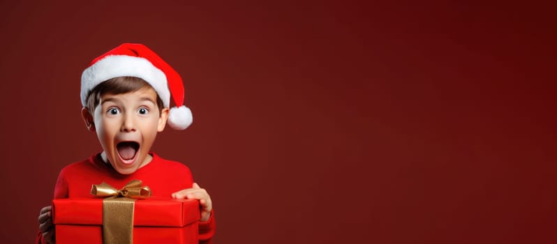 Surprised little boy in Santa Claus hat holding gift box. Christmas holidays. Boxing Day shopping. Holiday shopping.