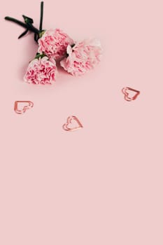 Roses on a pink background with three metal hearts.