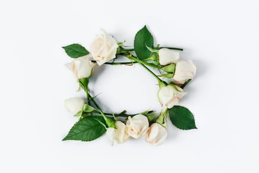 A small frame of white roses and green leaves on a white isolated background.