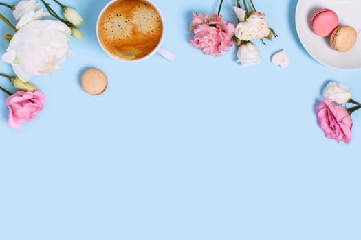 Blue background with macaroons and a Cup of coffee surrounded by peonies and roses. Top view with space for your text.