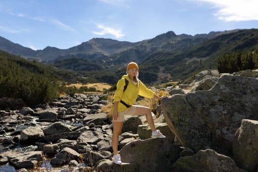 Excited woman walking through landscape outdoors. An active girl enjoys her vacation in the forested mountains. Smiling tourist on a hike. A joyful explorer going on a tourist adventure