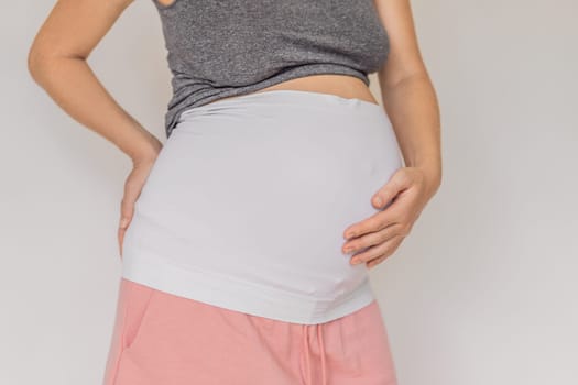 Pregnant bliss: Mom-to-be embraces her baby bump with a soft fabric bandage, providing gentle support. Maternity made comfortable.