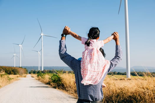 Father joyfully carries daughter exploring wind farm. Family bonding amid turbines signifies innovation in renewable energy. A joyful father-daughter moment in windmill industry. father day concept