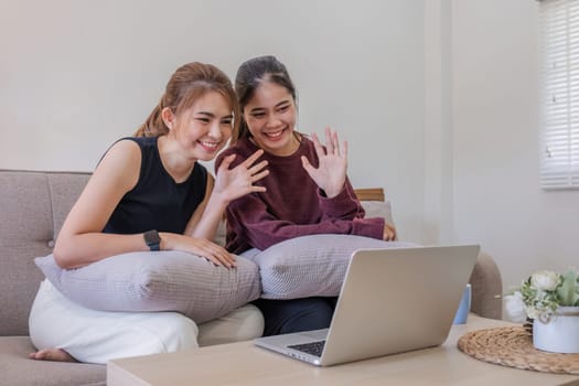 Two women communicate with friends and classmates via video link using laptop and smartphone in living room. Friends, friendship, time together..