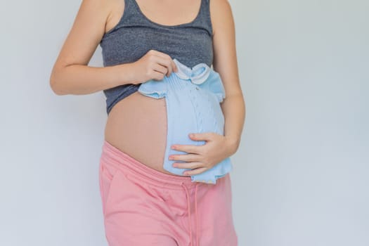 A tender moment: expectant mom cradling baby clothes against her growing belly, anticipating the joy of motherhood.