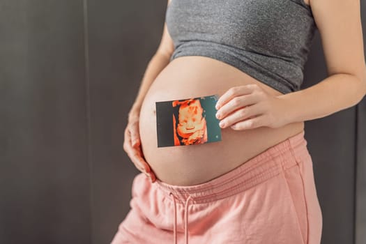 Expectant mother tenderly connects with her unborn child, holding ultrasound photo to her pregnant belly.