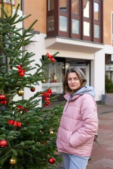 Elegance in the Old Town: Beautiful Woman Posing amidst the Festive Streets of Bietigheim-Bissingen, Germany . A beautiful girl stands on the street of the old European town of Bietigheim-Bissingen in Germany on Christmas Eve. City streets are decorated with Christmas trees and New Year's decorations, tourism, fashion, historical places, Europe