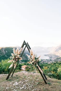 Triangular wedding arch wigwam stands on a mountain above the Bay of Kotor. Montenegro. High quality photo