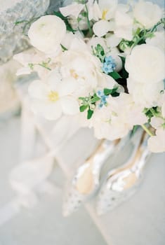Wedding bouquet stands on the table near bride shoes. Top view. High quality photo