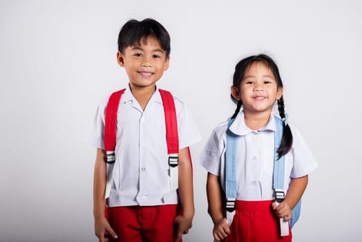 Two Asian student kid girl boy schoolchildren brother sister smile happy wear student thai uniform red pants skirt in studio shot isolated on white background, Portrait little children girl preschool