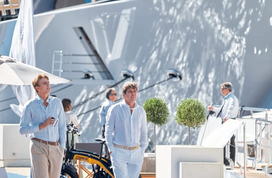 Monaco, Monte Carlo, 28 September 2022 - Invited wealthy clients inspect megayachts at the largest fair exhibition in the world yacht show MYS, port Hercules, yacht brokers, sunny weather. High quality photo