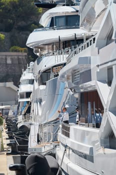 Monaco, Monte Carlo, 28 September 2022 - Invited wealthy clients inspect megayachts at the largest fair exhibition in the world yacht show MYS, port Hercules, yacht brokers, sunny weather. High quality photo