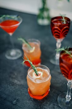 Orange cocktails in glasses with green twigs and pieces of fruit stand on the table. High quality photo