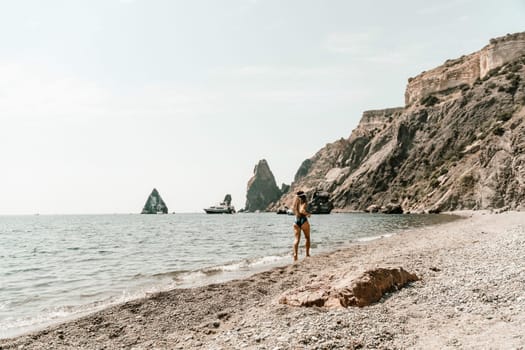 Woman beach vacation photo. A happy tourist in a blue bikini enjoying the scenic view of the sea and volcanic mountains while taking pictures to capture the memories of her travel adventure