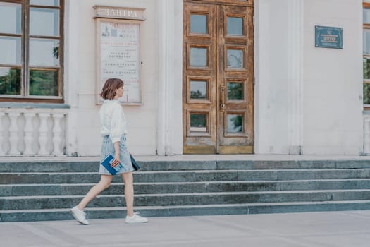 Woman staircase city. A business woman in a white shirt and denim skirt walks down the steps of an ancient building in the city.