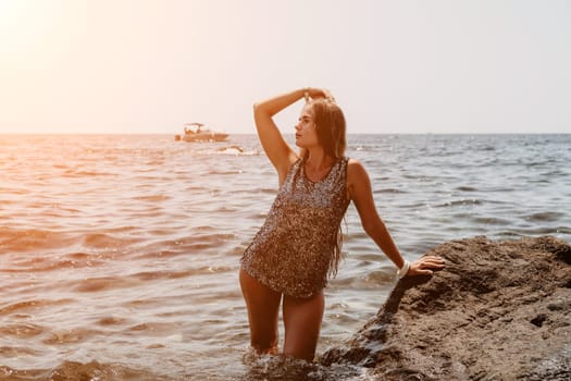 Woman travel sea. Young Happy woman in a long red dress posing on a beach near the sea on background of volcanic rocks, like in Iceland, sharing travel adventure journey