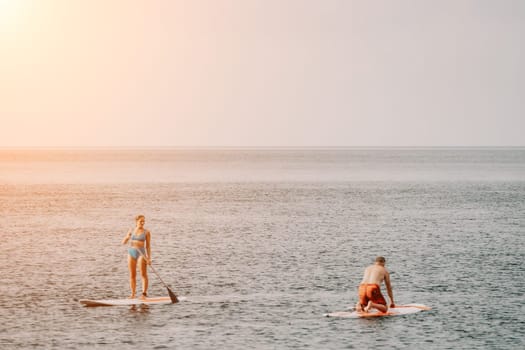 Active mature male paddler with his paddleboard and paddle on a sea at summer. Happy senior man stands with a SUP board. Stand up paddle boarding - outdor active recreation in nature