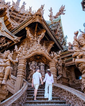 A diverse multiethnic couple of men and women visit The Sanctuary of Truth temple in Pattaya Thailand. It is a wooden temple construction located at the cape of Naklua Pattaya City Chonburi Thailand