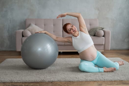 Pregnant woman doing side bends with a fitness ball at home