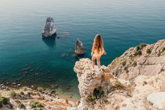 Woman travel sea. Happy tourist taking picture outdoors for memories. Woman traveler looks at the edge of the cliff on the sea bay of mountains, sharing travel adventure journey.