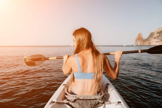 Woman in kayak back view. Happy young woman with long hair floating in transparent kayak on the crystal clear sea. Summer holiday vacation and cheerful female people relaxing having fun on the boat