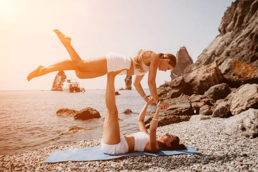 Woman sea yoga. Back view of free calm happy satisfied woman with long hair standing on top rock with yoga position against of sky by the sea. Healthy lifestyle outdoors in nature, fitness concept.