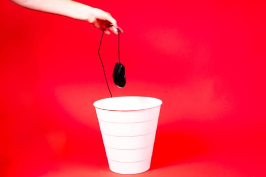 A computer mouse with a wire is thrown into a office wastebasket.